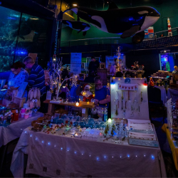 Market-type stalls in a darkened room with string fairy lights and people shopping