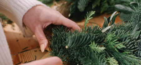 Photo of a lady making a Christmas wreath with fresh green foliage