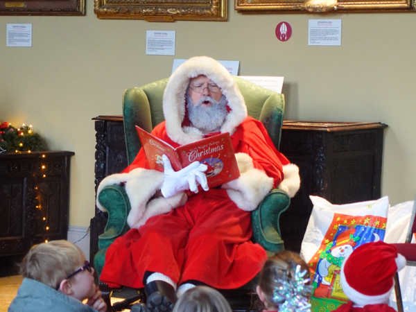 Santa sitting and reading The Night Before Christmas to children