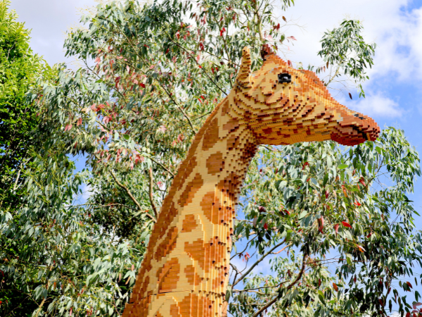 A brick-built giraffe is visible from mid-neck up with tree foliage behind