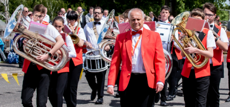 Marching brass band wearing red jackets and bowties