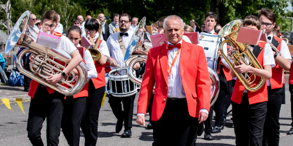 Marching brass band wearing red jackets and bowties