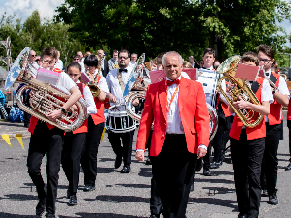 Marching brass band wearing red jackets and bowties