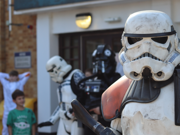 Star Wars Stormtrooper staring at the camera. People and more characters in background.