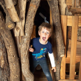 Child peeping out of William's Den Tree House