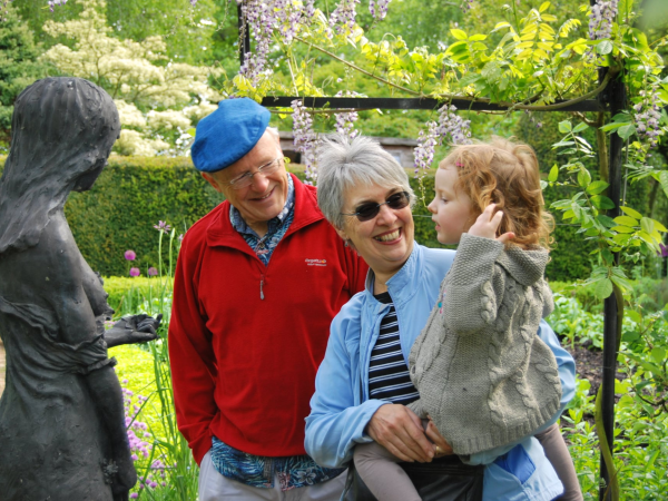 A man and a woman smile whilst holding a child who is enjoying the gardens