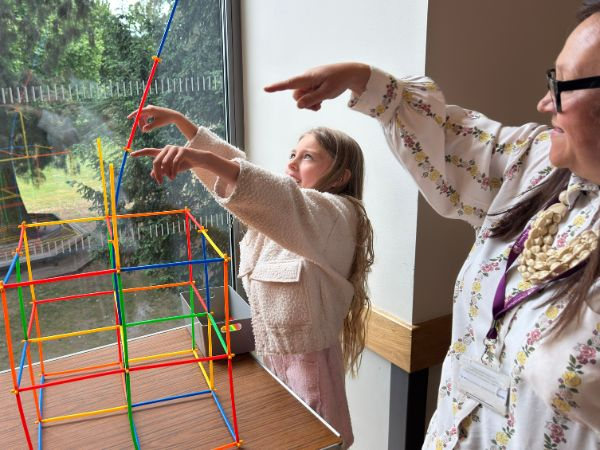 A child stands in the middle of the picture, while a museum educator teaches them in one of the home education learning session.