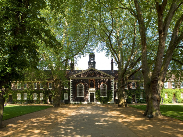 The facade of Museum of the Home's almshouse and chapel surrounded by green trees