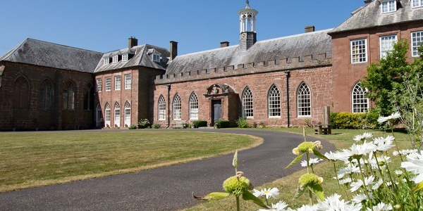 The exterior of Hartlebury Castle on a sunny day with flowers in the foreground