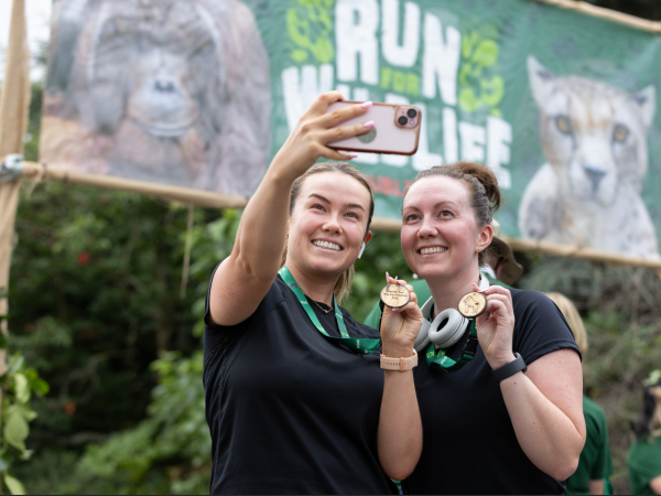 Participants in green “Run for Wildlife at Dublin Zoo” take a selfie with their medals at the finish line.