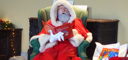 Santa sitting and reading The Night Before Christmas to children