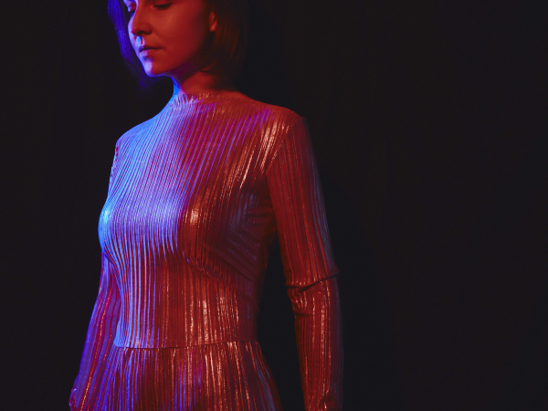 A woman in a silver dress, illuminated by a red light.