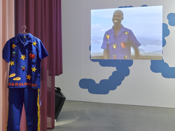 A royal blue boiler suit designed by Harold Offeh. The suit is covered in bright patches and shapes.