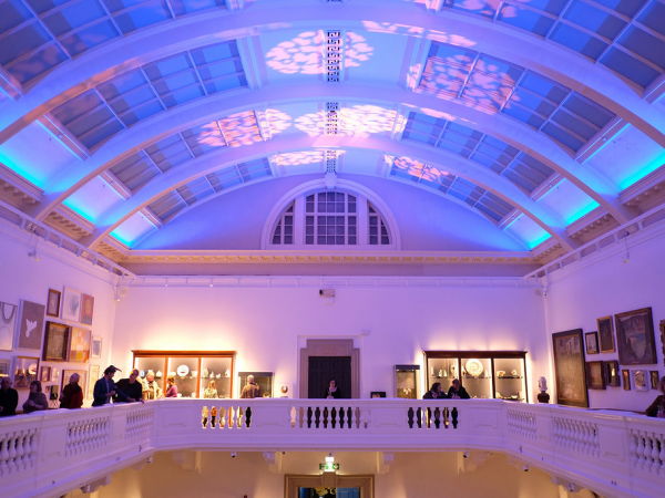 An image of the balcony inside of the museum in 'party mode' with blue lights across the ceiling.