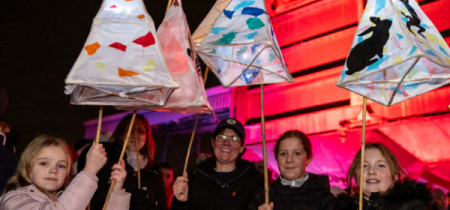 4 people stood holding handmade lanterns in the Museum's Pit Yard