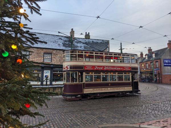 Tram in 1900s town with christmas tree and lights.