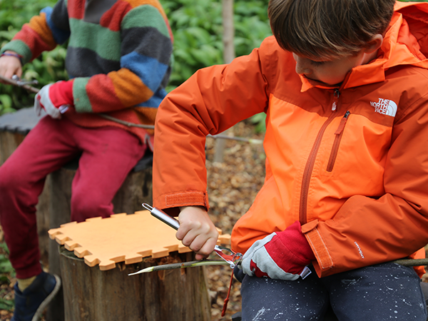A boy carving as part of Forest School