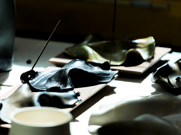 A stylish, swooping incense stick holder in bright sunlight.