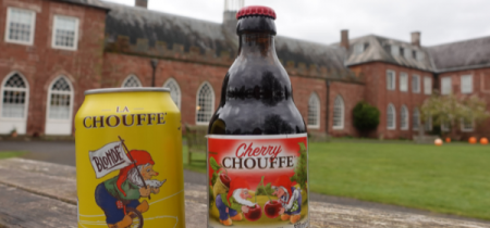 A Chouffe beer bottle and can in front of the Hartlebury Castle exterior