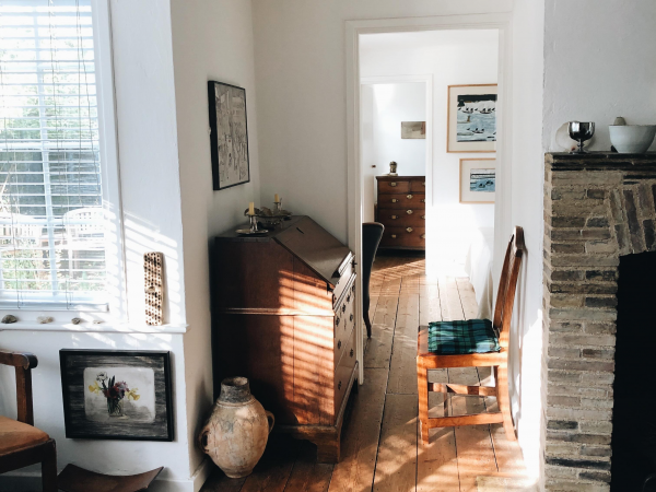 A sitting room in a cottage, with a large bay window and a bureau in the corner.