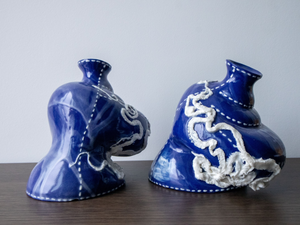 two blue ceramic vessels with white textured designs, shaped as if they are melting to one side.