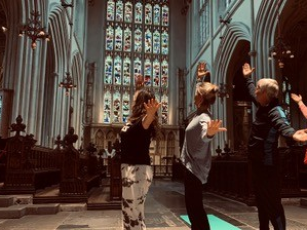Group of people stretching in the Abbey in front of the stained glass window
