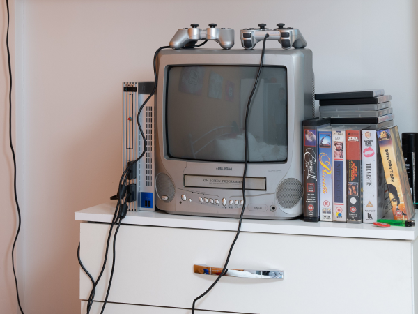 An image of a TV with built in VHS player from the Museum's 2005 room display. A collection of VHS cases are shelved beside the TV.