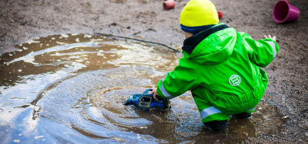 A child plays with a toy car in a mud