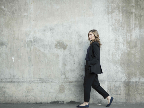 A woman walking past a concrete wall.