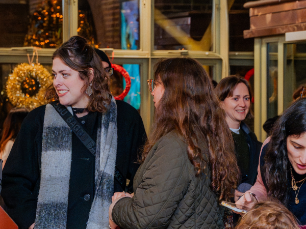 People in winter coats enjoy an indoor gathering.