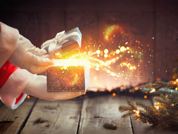 Santa Claus opens a silver gift box, releasing magical sparkles in a festive holiday setting.