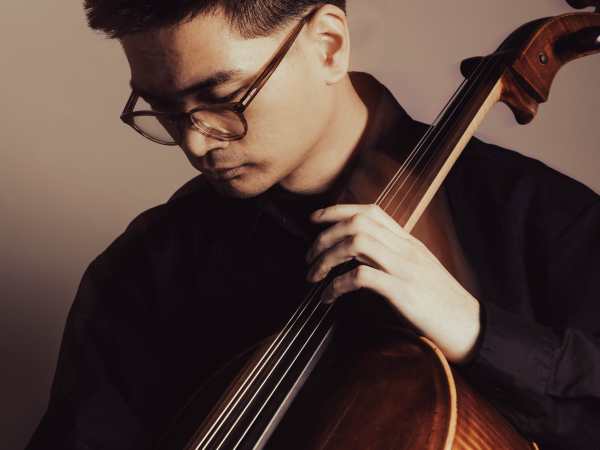 A portrait of Ezra Escobar holding a cello.