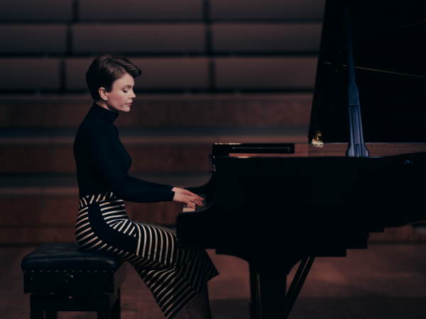 A woman with short brown hair playing a piano.