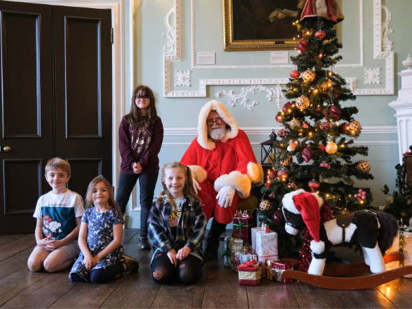 Children posing with Santa by a Christmas tree inside Hartlebury Castle