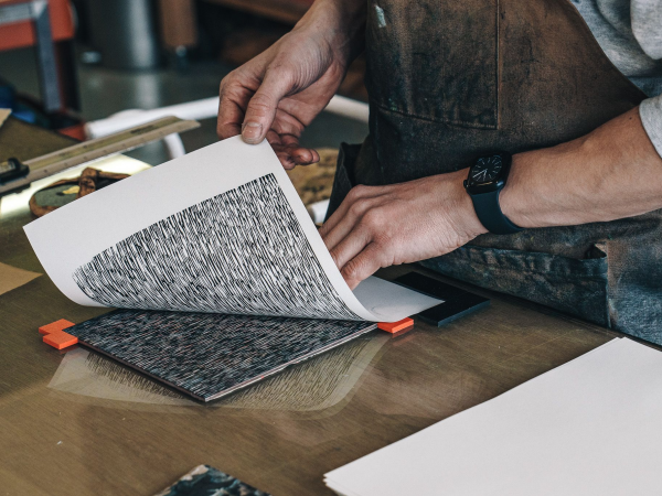 A person's arms printing a pattern onto paper in a workshop