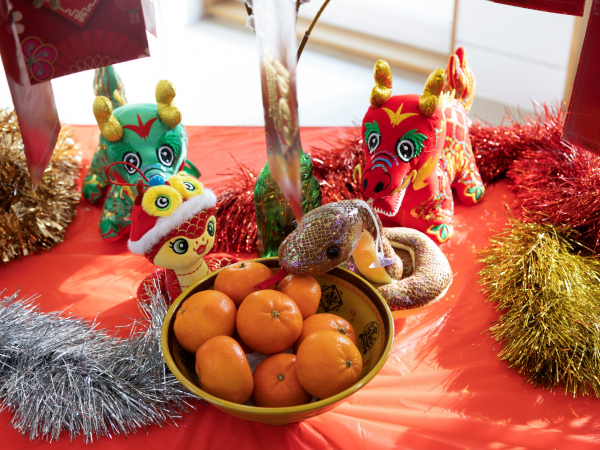 red table with colourful tinsel, a bowl of oranges and some stuffed animals
