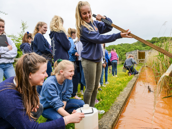ChildreChildren sampling orange water through the reed beds