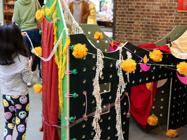 a young child plays with a wooden house structure decorated with fabrics.