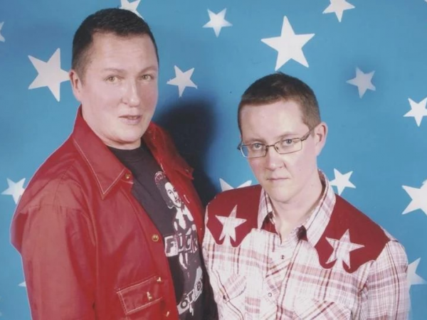 The two founders of Transfabulous pose in front of a blue wall with white stars.