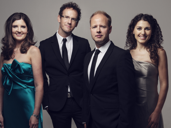 Two men in suits and black ties, and two women in bright dresses.