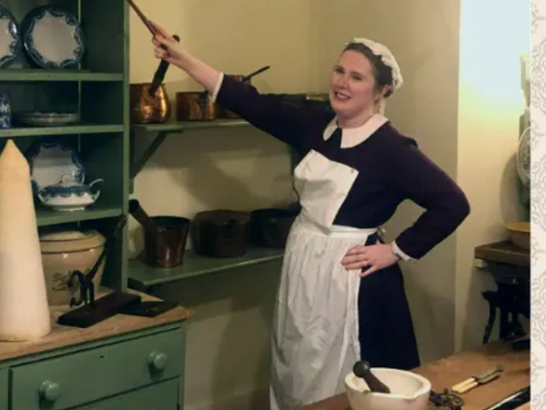 Rachel dressed as Maud Butcher cleans a shelf in the Victorian Kitchen