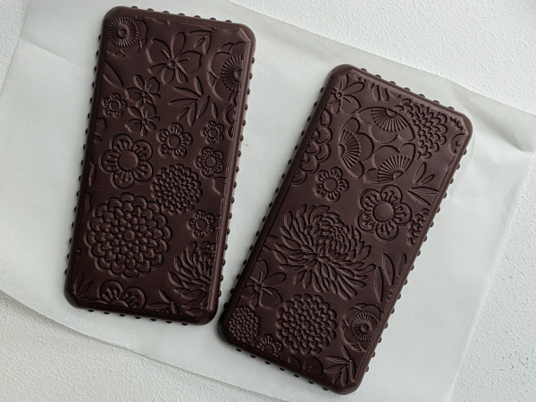 Two dark handmade chocolate bars, with ornate floral textured design